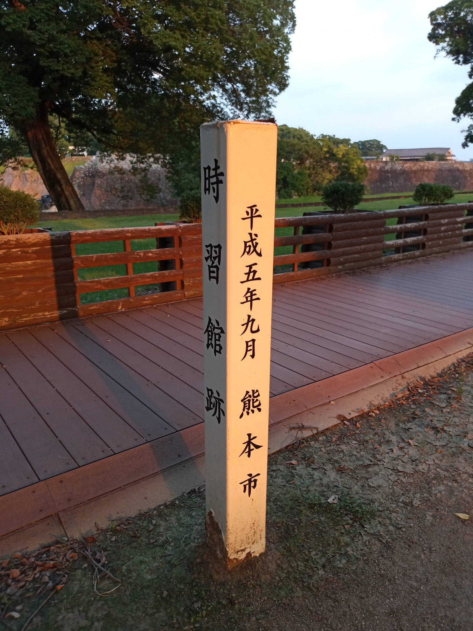 「時習館跡」と記された標柱。背景に西出丸の石垣が見える。